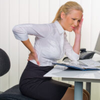 Frauen im Büro mit Rückenschmerzen
