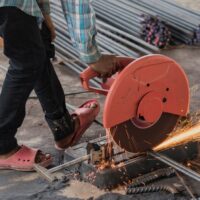 Construction builder worker with grinder machine cutting metal reinforcement rebar rods at building site and unsafe Construction builder worker with grinder machine cutting metal reinforcement rebar rods at building site and unsafe