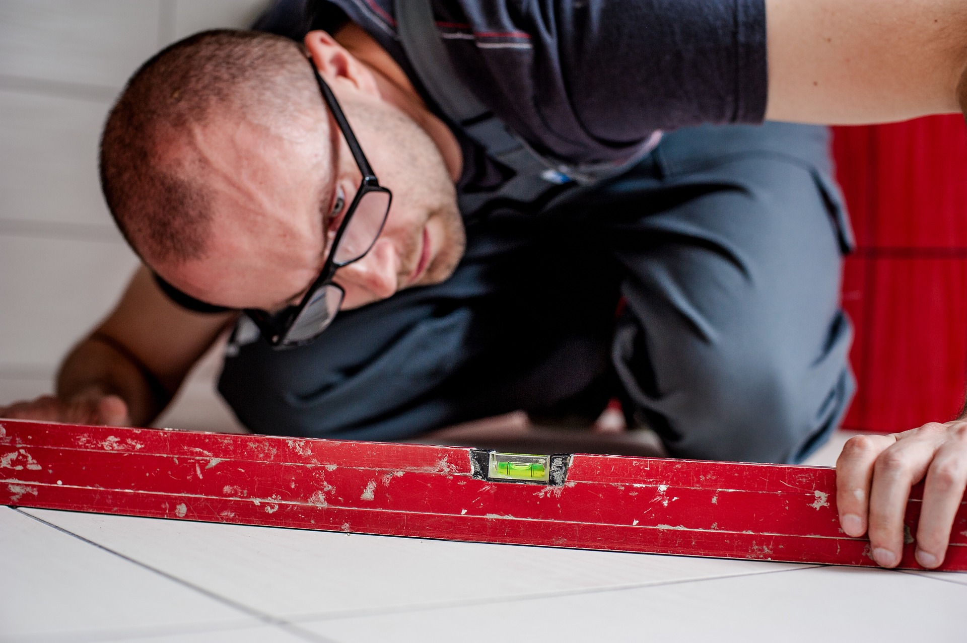 Man measures tiles on floor.