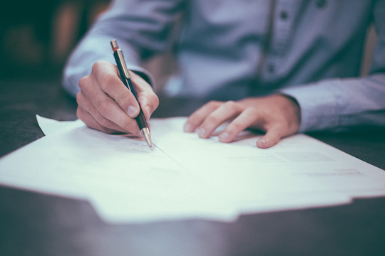 Man signing paperwork at a desk.