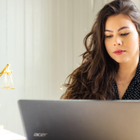 Woman using laptop on table with sculpture of Lady Justice. Woman using laptop on table with sculpture of Lady Justice.
