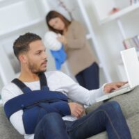 Man with arm injury using laptop