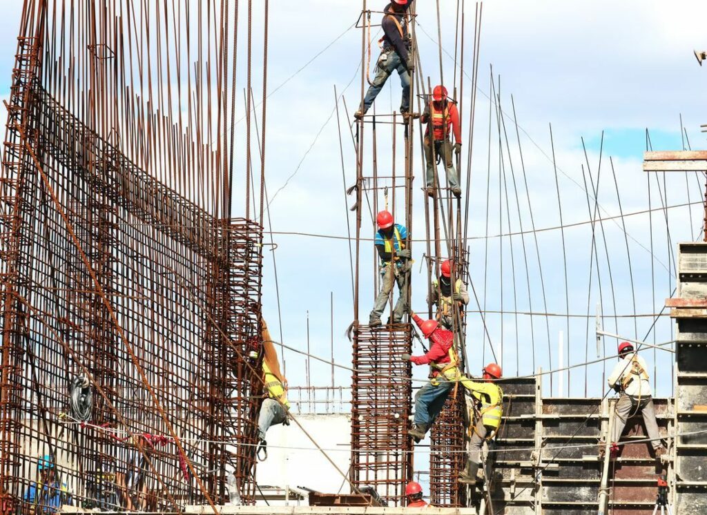 Construction workers setting up hundreds of metal poles and trying to avoid injury.