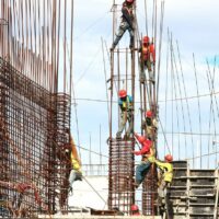 Construction workers setting up hundreds of metal poles and trying to avoid injury.