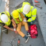 Construction worker has an accident at a construction site. Emergency help engineers provide first aid to construction workers in accidents. Safety team help a construction worker who has an accident.