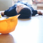Yellow helmet of injured lying worker at work. Dangerous accident in warehouse during work