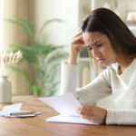 Sad woman reading letter on a wooden table at home
