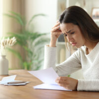 Sad woman reading letter on a wooden table at home
