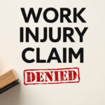 Text reading "WORK INJURY CLAIM" appears in bold black, with a red stamped "DENIED" below. A wooden stamp lies to the left on a light background.