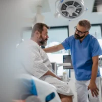 Supportive doctor soothing a worried overweight patient, discussing test result in emergency room. Illnesses and diseases in middle-aged men's health. Compassionate physician supporting stressed