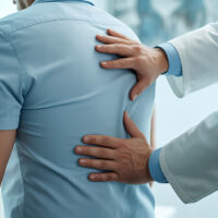Doctor examining a patient's back in a medical consultation checking spine and posture Doctor examining a patient's back in a medical consultation checking spine and posture