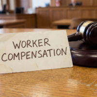Worker compensation legal claim concept with judge gavel in courtroom setting representing occupational injury lawsuit employee rights enforcement and workplace injury financial settlement process Worker compensation legal claim concept with judge gavel in courtroom setting representing occupational injury lawsuit employee rights enforcement and workplace injury financial settlement process